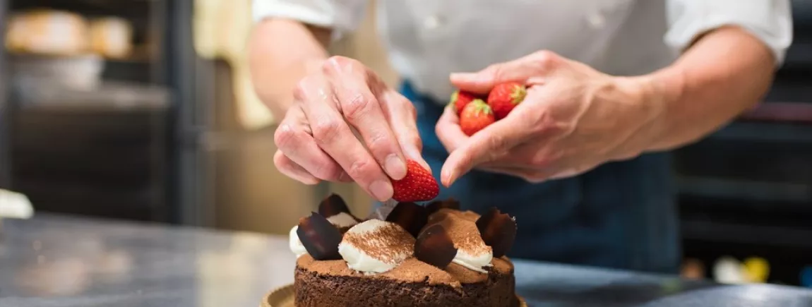 Un chef patissier élabore un gâteau au chocolat et aux fraises