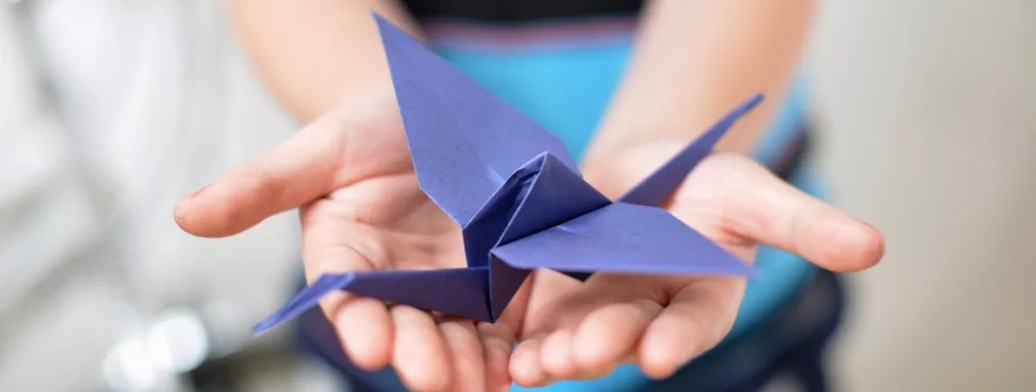 Un enfant tient un oiseau en origami dans ses mains