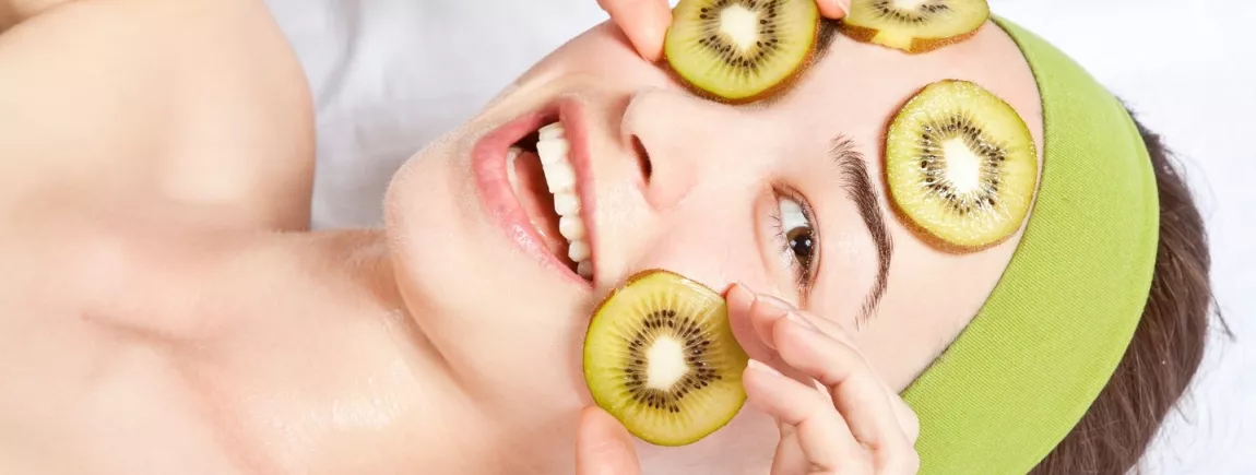 Une femme dispose des tranches de kiwi sur son visage