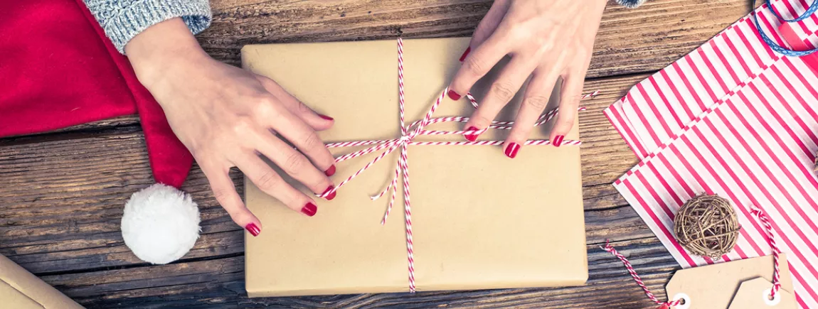 Un livre de cuisine au pied du sapin Une femme emballe un livre de cuisine pour l’offrir à Noël