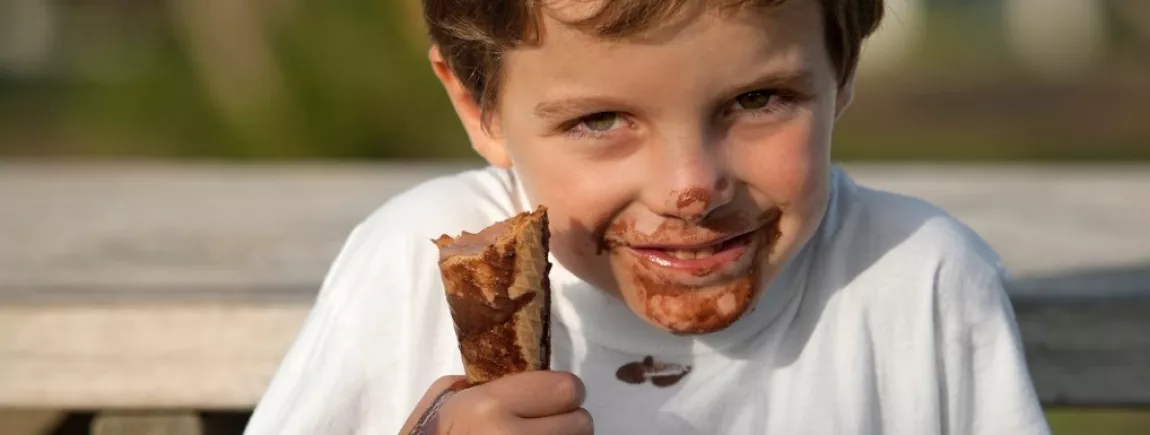 Un enfant mange une glace au chocolat en se tachant