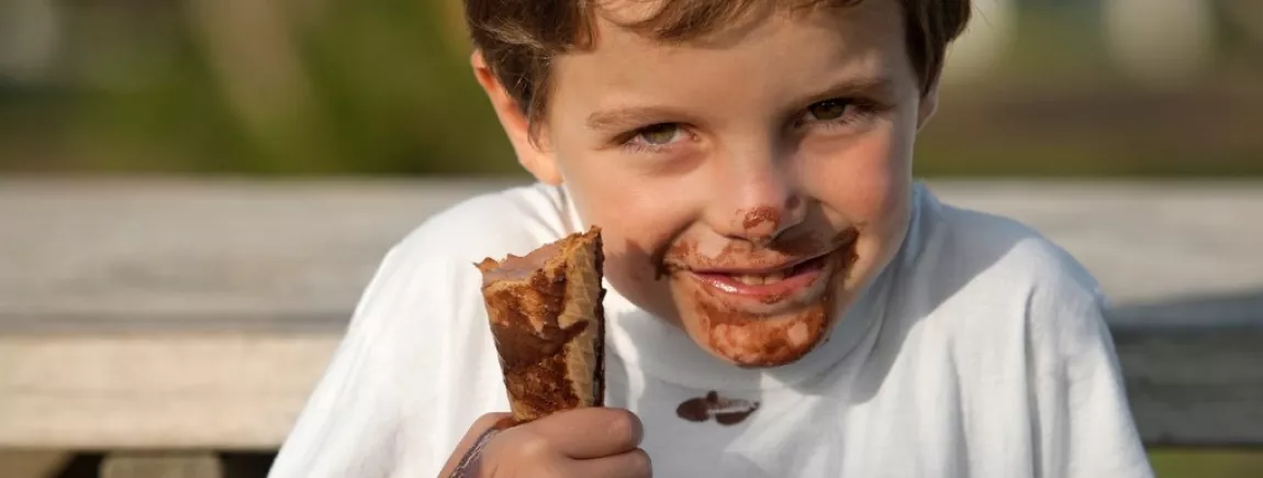 Une glace qui ne coule pas sur les doigts Un enfant mange une glace au chocolat en se tachant