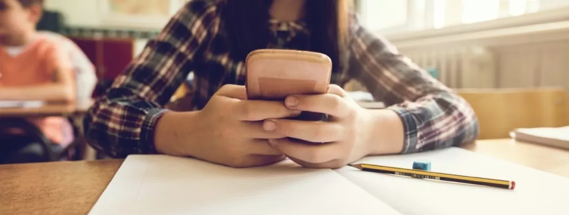 Plus de portables dans la classe ! Une jeune élève qui utilise son portable en classe