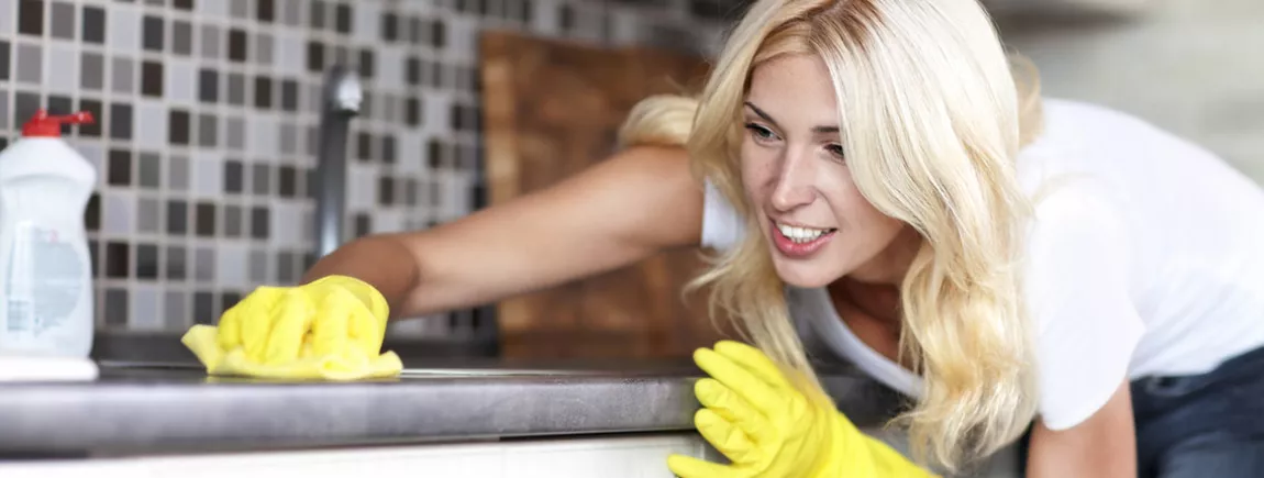 Cuisine : la chasse aux bactéries est ouverte ! Une femme nettoye sa cuisine avec un produit d’entretien.