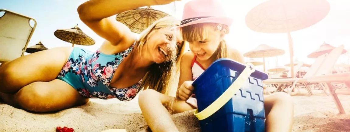 Une mère et sa fille jouent avec du sable sur une plage