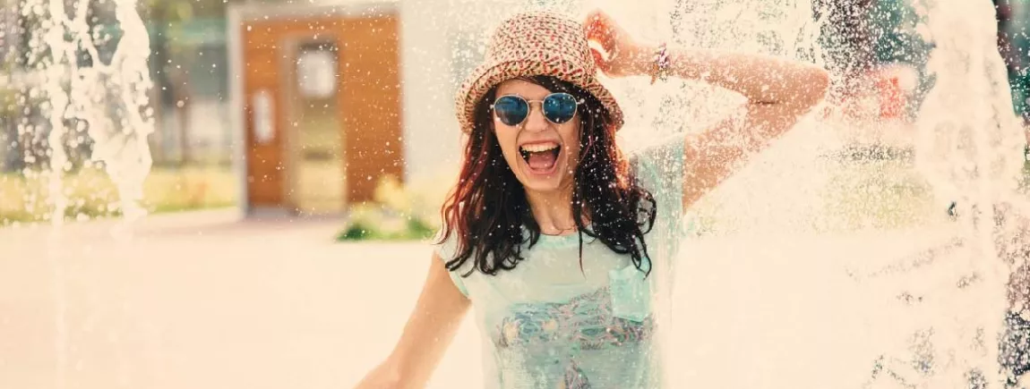Malin : le kit anti-canicule ! Une femme se rafraichit dans des jets d’eau
