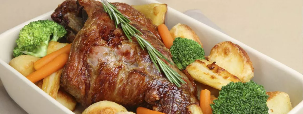 Gigot d’agneau servi à table dans son plat et ses légumes