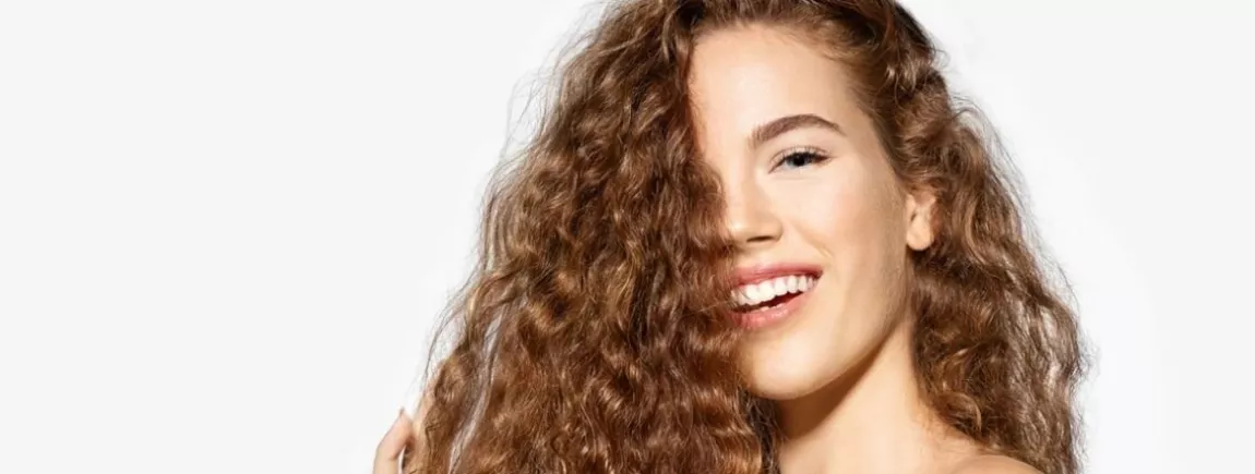 Affichez fièrement vos boucles ! Cheveux frisés. Cheveux bouclés. Soin des cheveux. Jeune femme souriante. Boucles.
