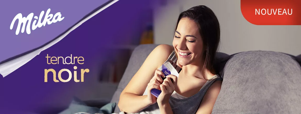 Découvrez le chocolat noir à la Milka ! Une femme déguste Milka Noir sur son canapé
