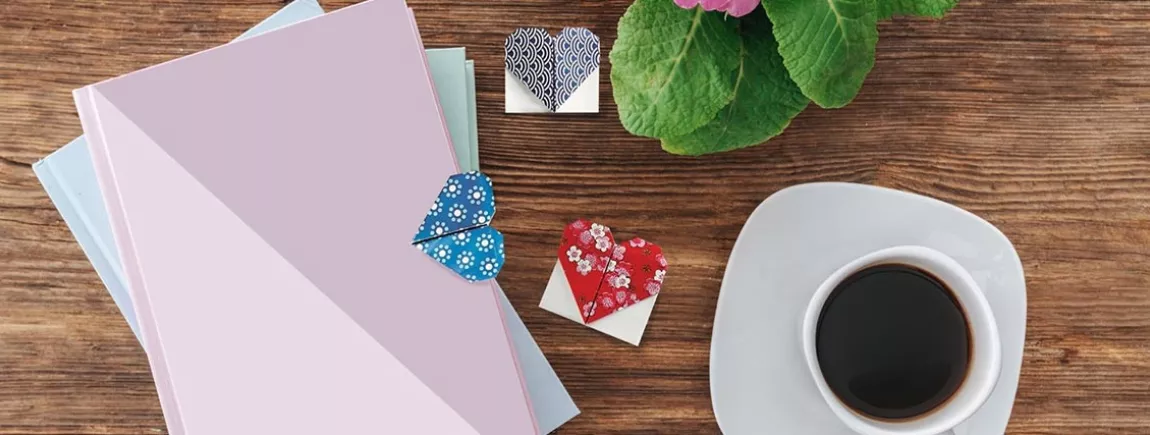 Un DIY de marque-page cœur en origami Des livres posés sur une table