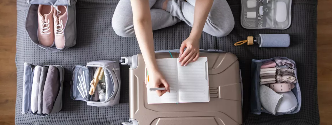 Nos astuces de pro pour voyager léger Jeune femme rangeant sa valise