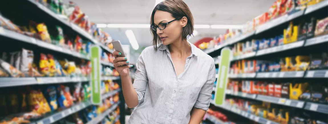 Une femme regardant son smartphone faisant les courses