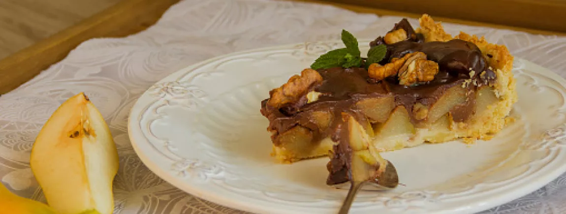 Tarte rustique poire, amandes & chocolat Côte d’Or Une part de tarte poire chocolat dans une assiette.
