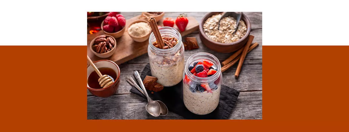 Deux pots de porridge aux fruits rouges posés sur une table, avec du chocolat Côte d’Or et des fruits secs