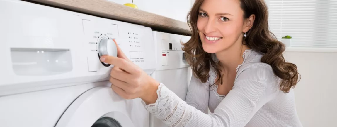Lave-linge : les trucs et astuces pour le garder longtemps Une femme programme son lave-linge